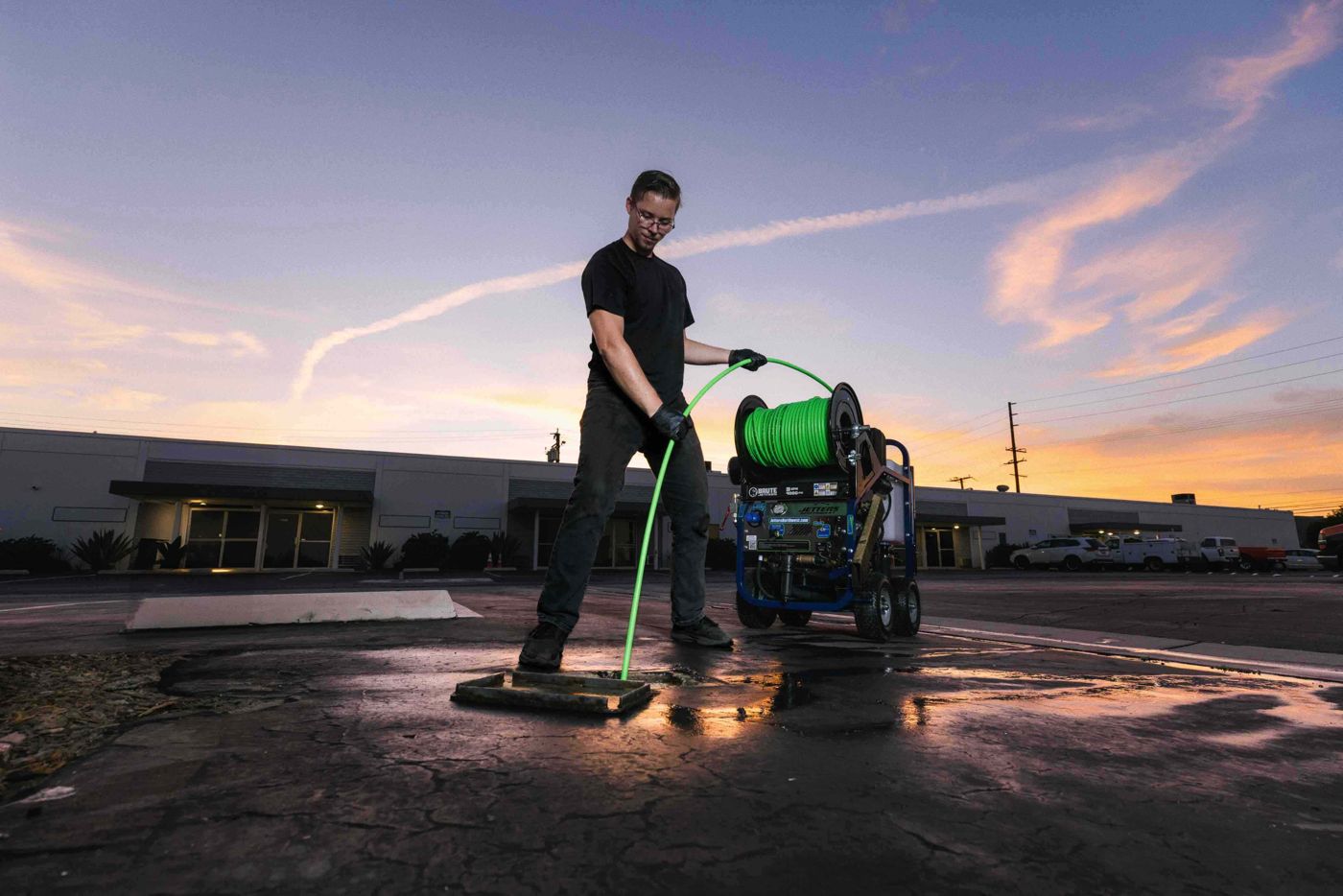Plumber feeding jetter hose into a storm drain from a Brute cart jetter