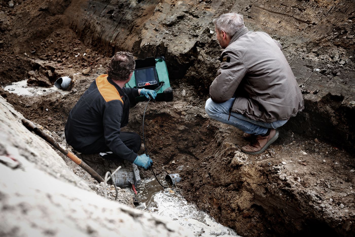 Plumbers running the MiniFlex into an excavated sewer line