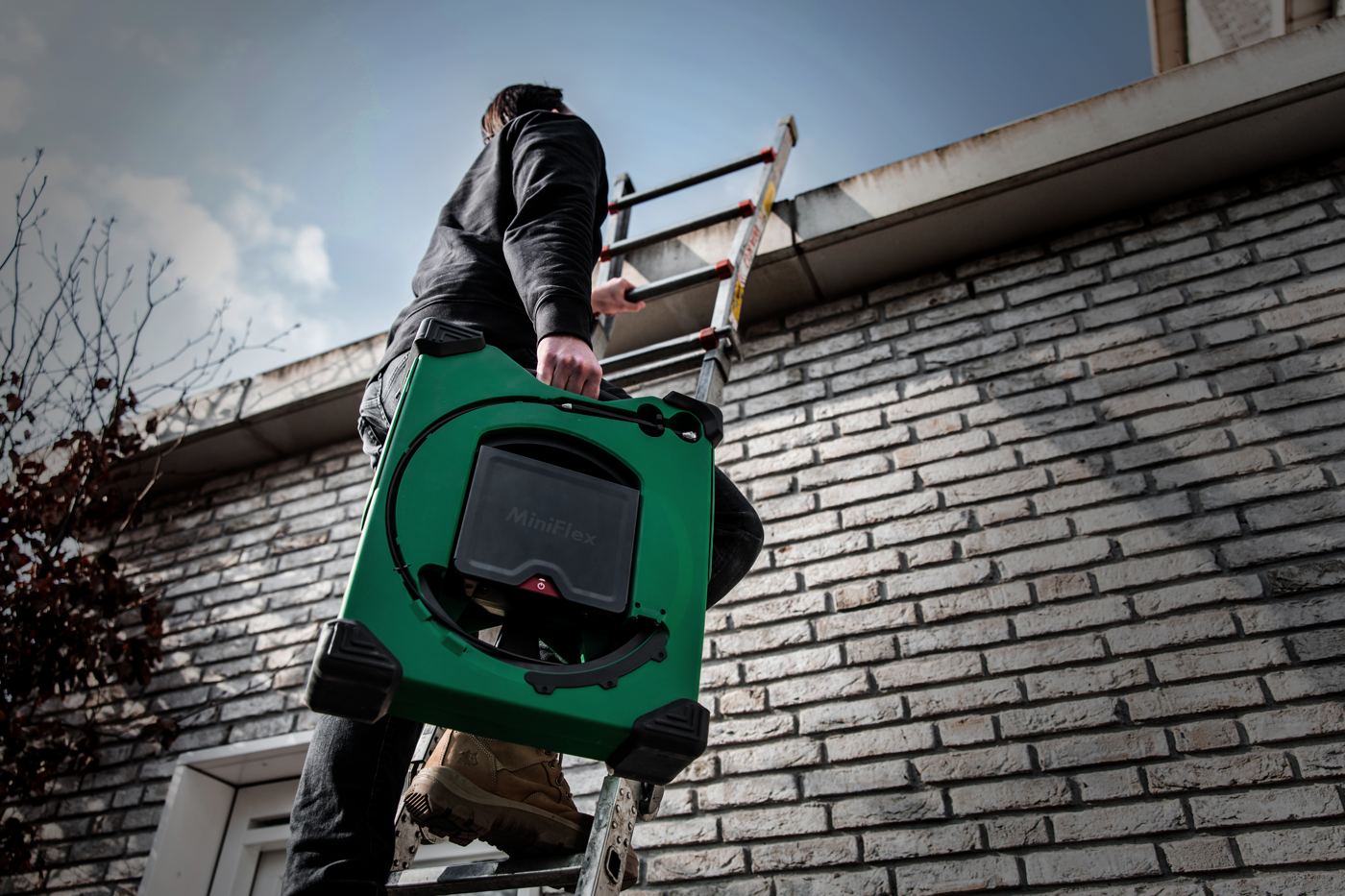 Plumber carrying the MiniFlex up a ladder to a roof